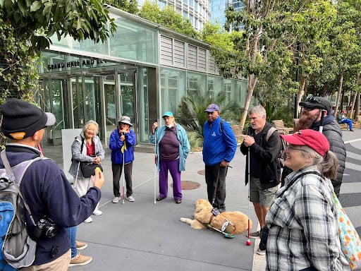A group of eight people and one dag talking in a circle outside.